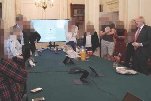 Mr Johnson stands side by side with at least nine other people. Their faces are pixelated.