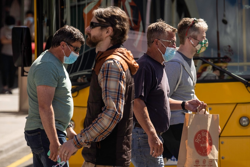 People wearing masks and one person without.