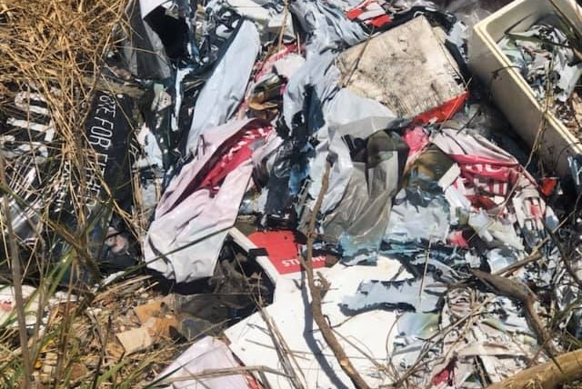 A large pile of material including election campaign signs in long grass