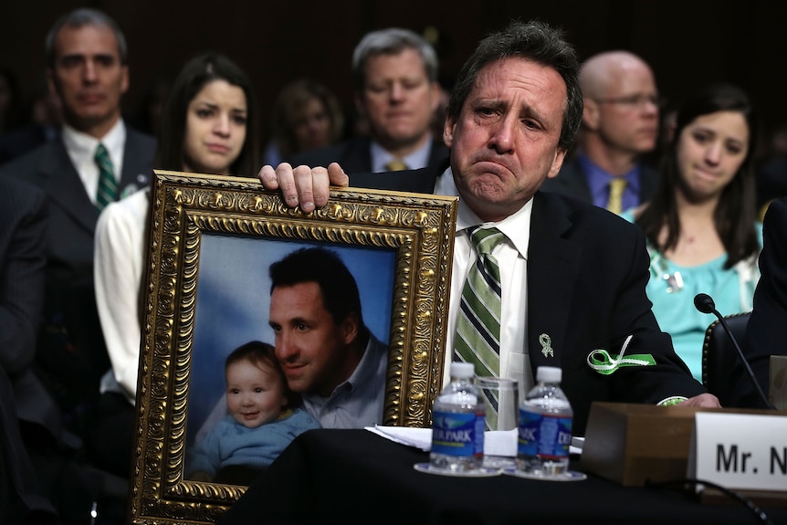 Neil Heslin holding a framed photo of himself and his baby Jesse Lewis. 