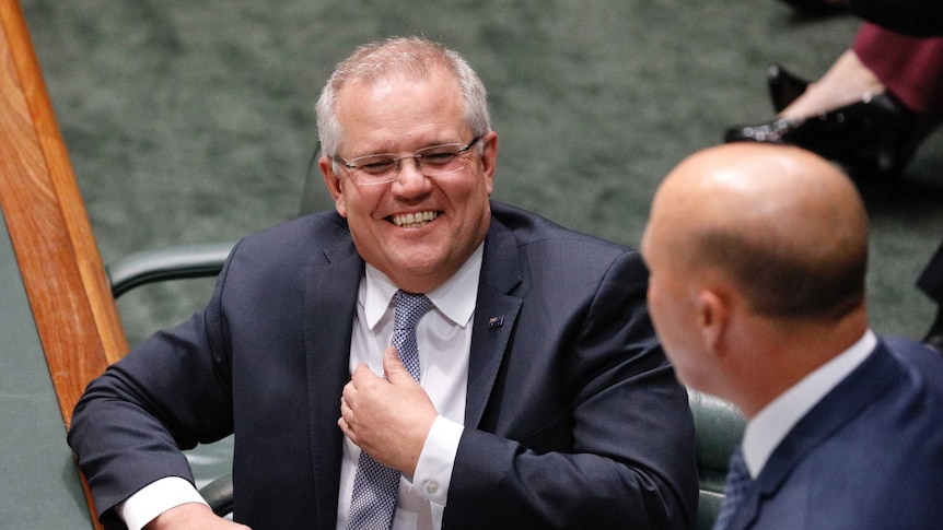 Scott Morrison is laughing as he looks at Peter Dutton who is addressing Parliament
