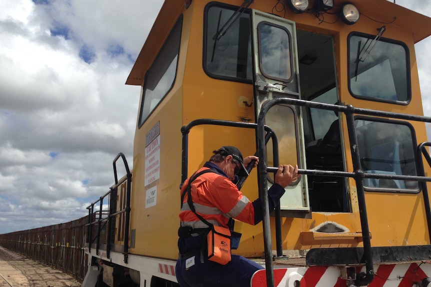 A cane-train driver climbs onto his locomotive.