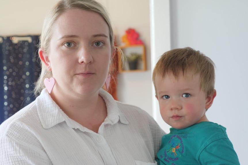 A woman wearing white holding her son