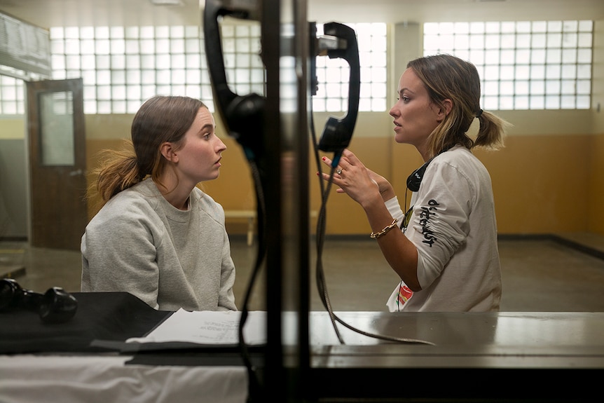 Colour production photo of director Olivia Wilde directing actor Kaitlyn Dever on the set of 2019 film Booksmart.