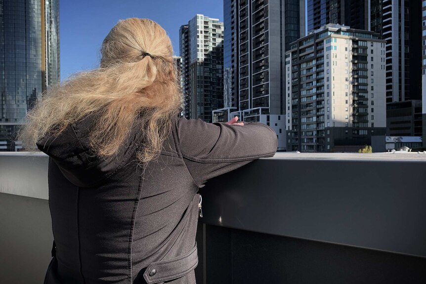 A non-identifiable image of a woman staring out onto Melbourne's city skyscrapers