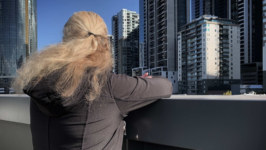 A non-identifiable image of a woman staring out onto Melbourne's city skyscrapers