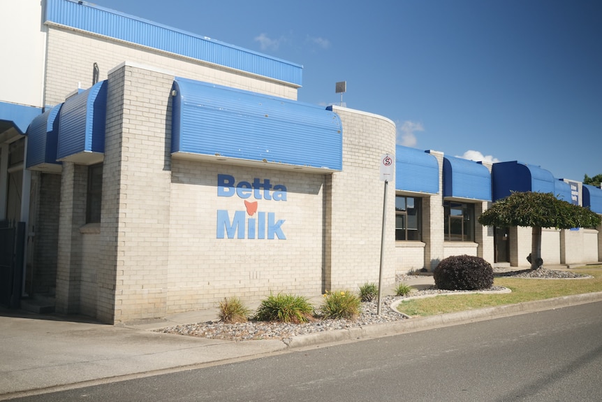 A white brick buildingwith blue awnings and the words "Betta Milk"