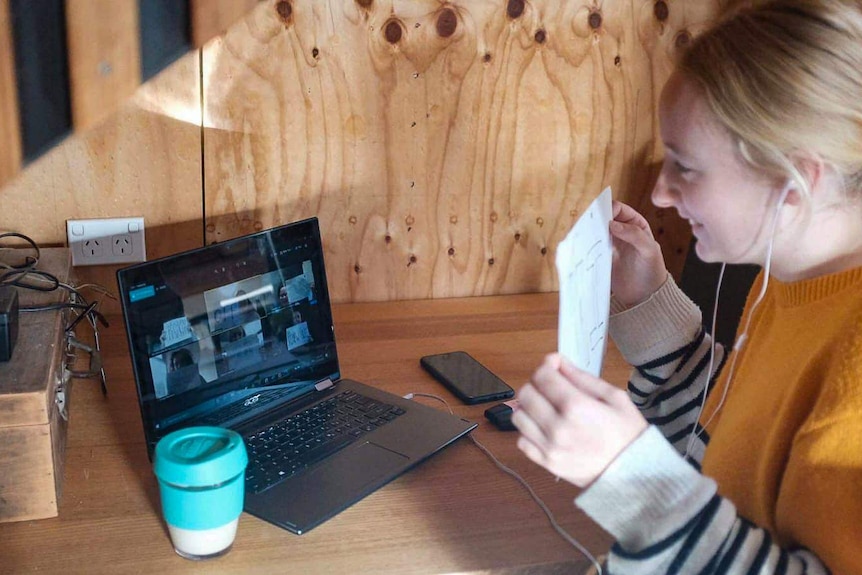 Gabrielle Dewsbury holds up a sign on a video conference with colleagues.