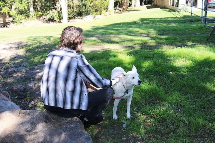 Dion [not his real name], sits with his dog in Brisbane in August 2017.