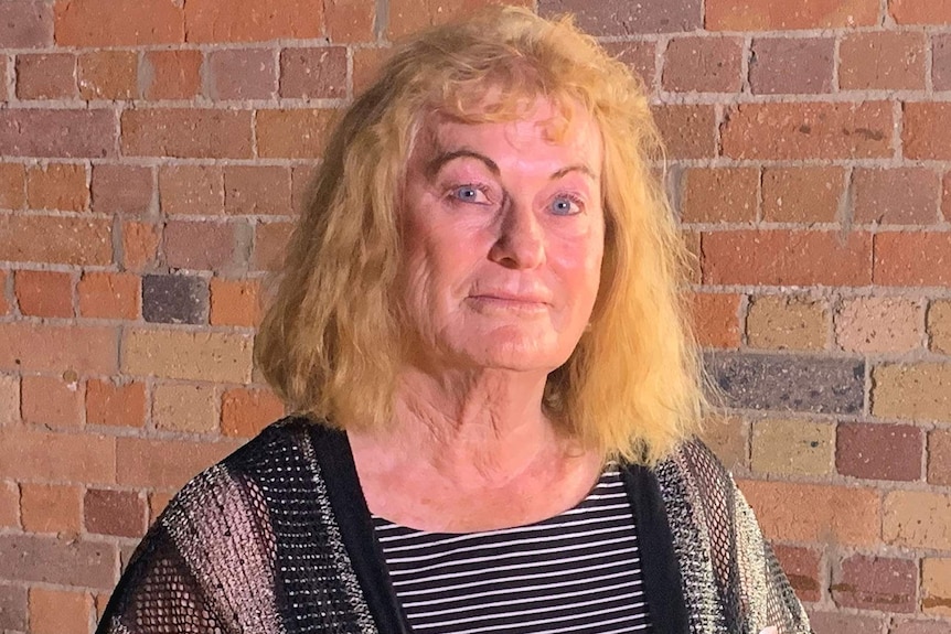 A woman standing in front of a brick wall