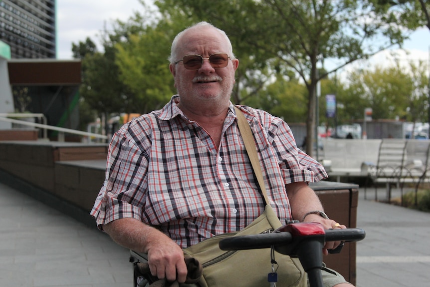 A photo of a man smiling at the camera on a mobility scooter
