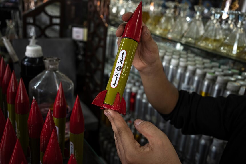 Hands holding up a perfume container that looks like a small rocket.