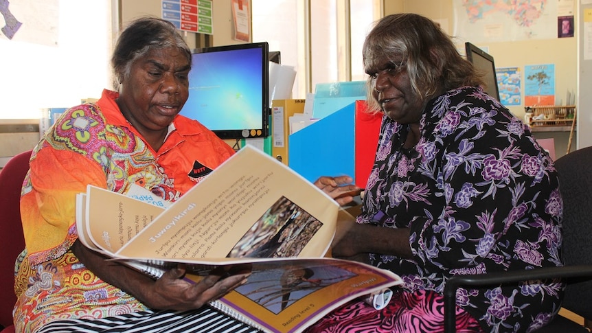 Two women read a book