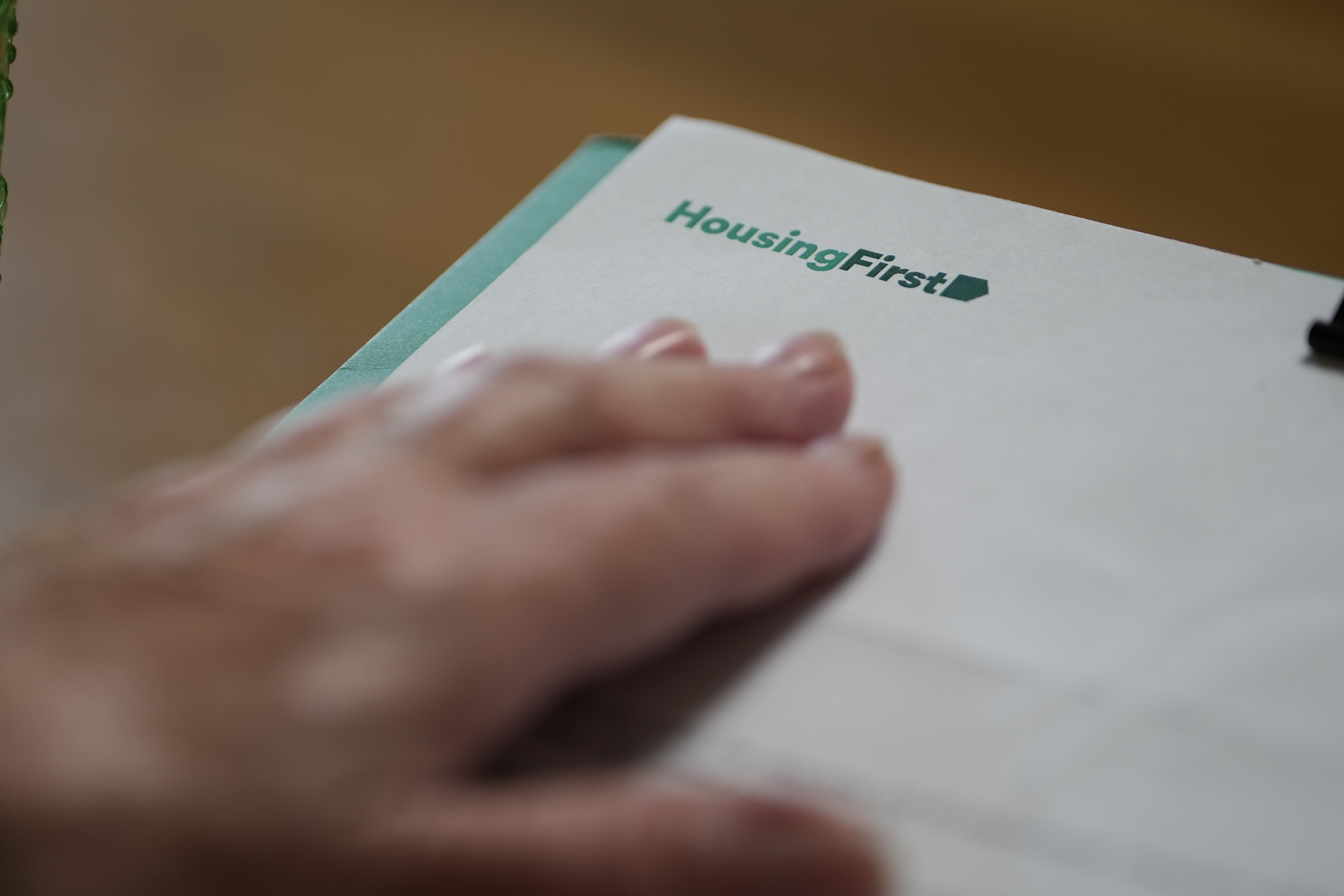Una mano descansa sobre una letra con el logotipo de Housing First en la esquina superior izquierda.