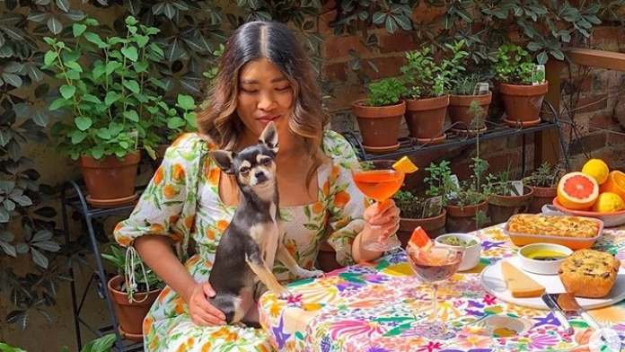 Melbourne woman Jessica Nguyen sits at a colourful table holding a dog.