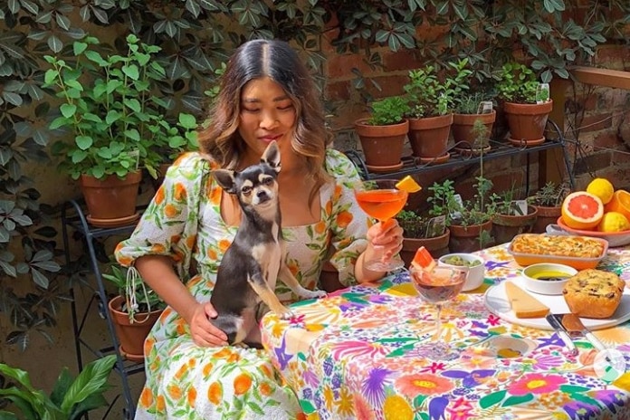 Melbourne woman Jessica Nguyen sits at a colourful table holding a dog.