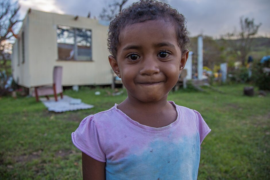 Little girl in front of cyclone-damaged houses