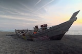 A wrecked fishing boat washed ashore with tangled ropes.