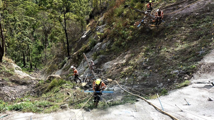 Abseilers transport heavy drilling equipment into the Binna Burra Road construction site.