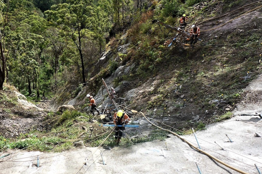 Abseilers transport heavy drilling equipment into the Binna Burra Road construction site.