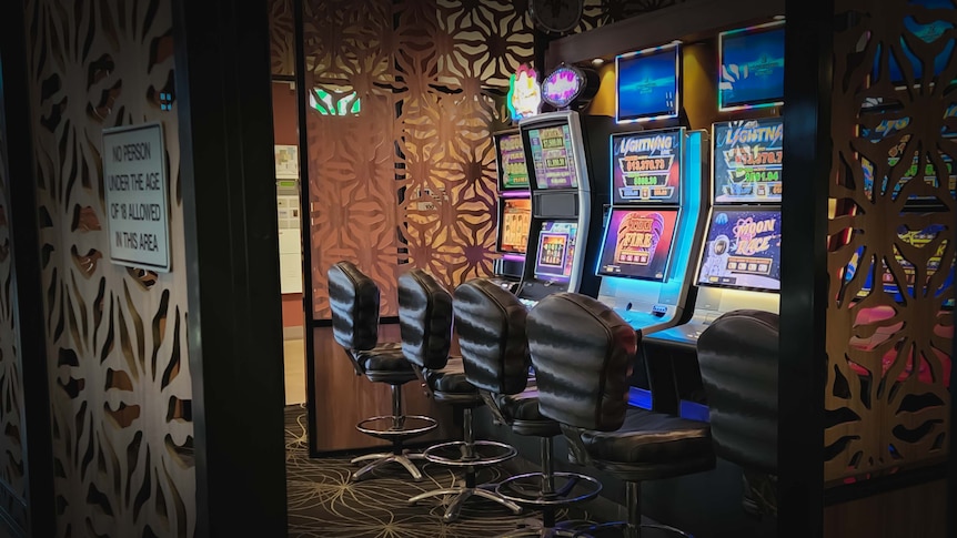 Three gaming machines sit empty in a pub.