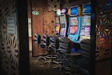 Three gaming machines sit empty in a pub.