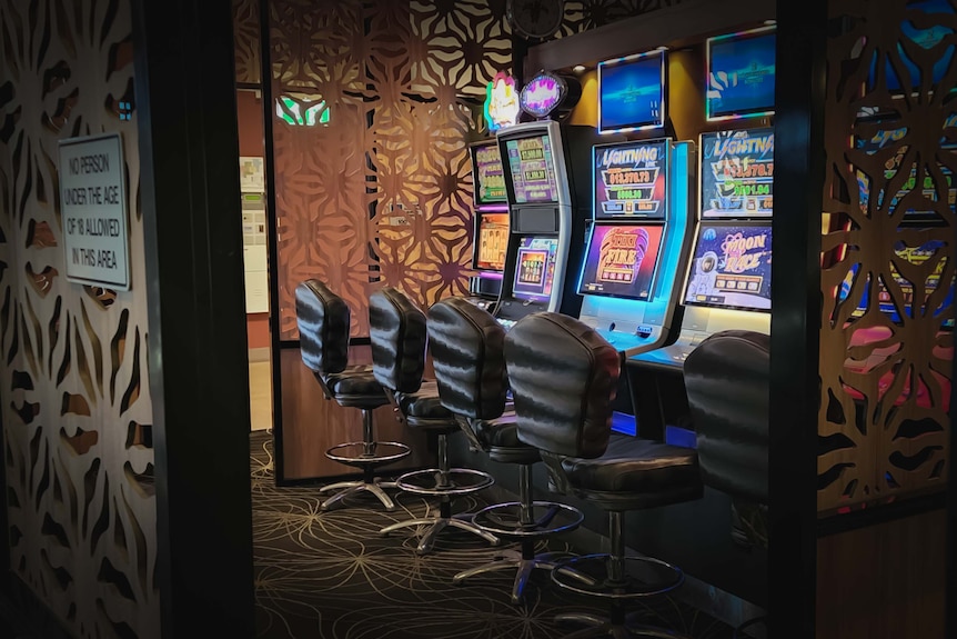 Three gaming machines sit empty in a pub.