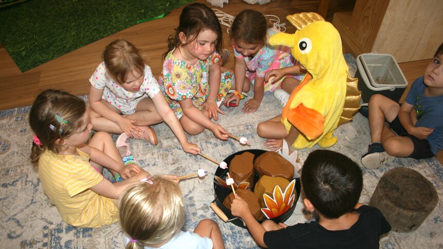 Children sit around a campfire in a guided drama performance, inspired by a little Bluey ‘Magic’. 