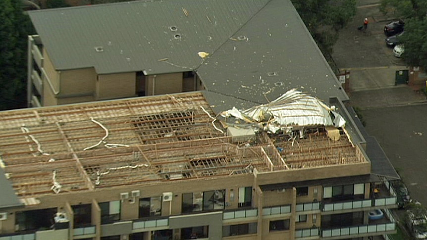 An aerial view of an apartment block with a section of roof missing.