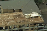 An aerial view of an apartment block with a section of roof missing.