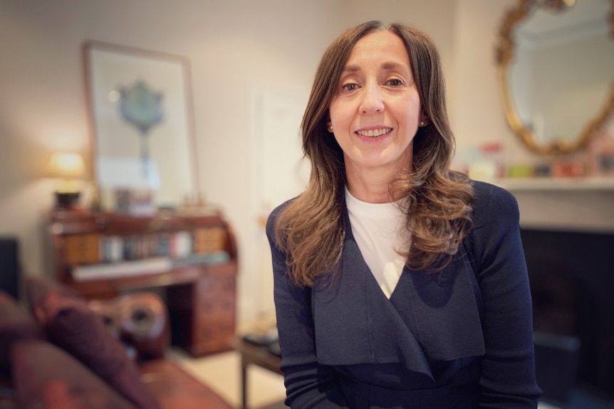 A woman sits on a chair and smiles at the camera