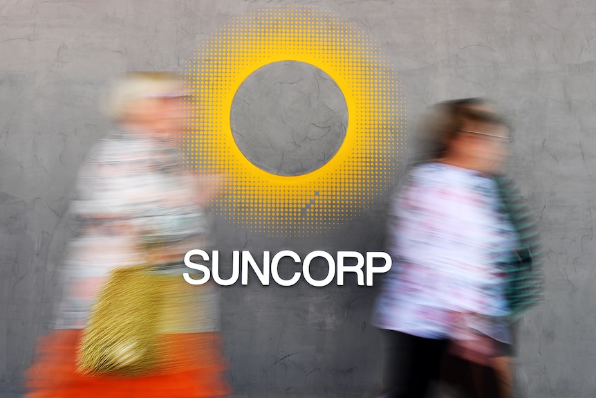 A blurred photo of two people walking by as the Suncorp name under a bright yellow circle is displayed. 
