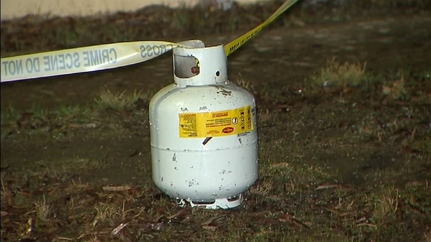 A gas bottle on the ground with police crime scene tape attached