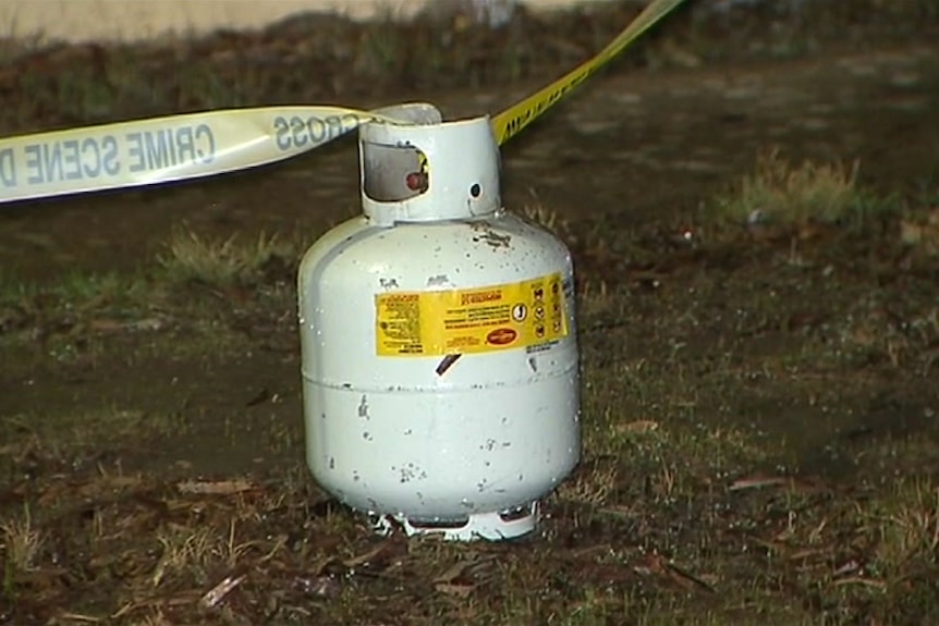 A gas bottle on the ground with police crime scene tape attached