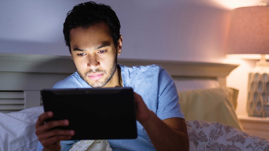 Man uses tablet device in bed