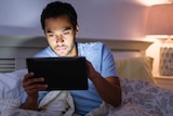 Man uses tablet device in bed