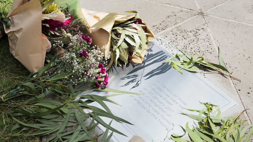 Flowers are laid on the ground near a plaque recognising victims of the Bourke Street Mall tragedy.
