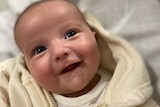 A smiling baby with mouth open.