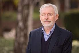 A portrait shot of an older man with white hair and beard.