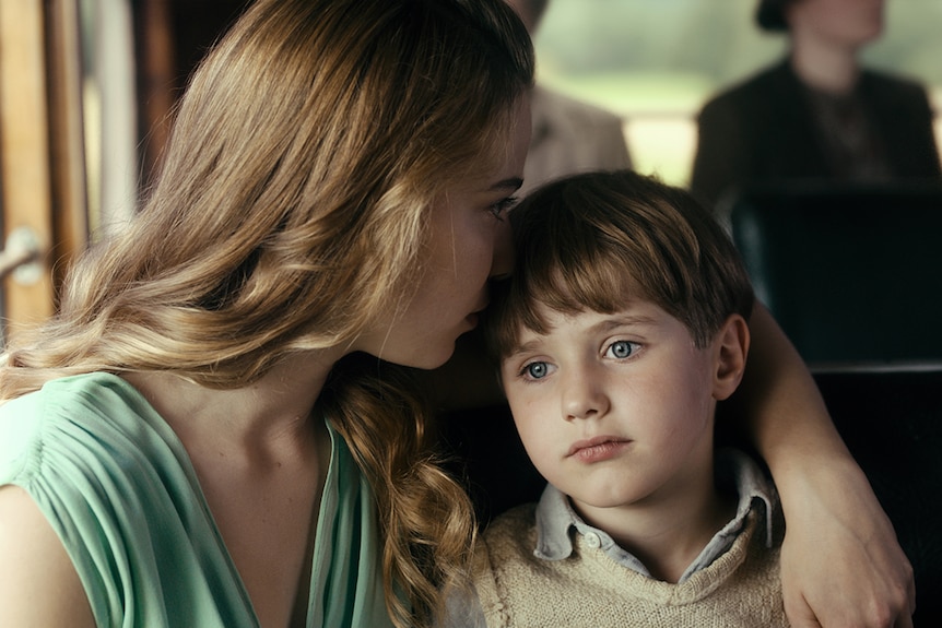 Colour still of Saskia Rosendahl with her arm around Cai Cohrs, both seated on bus in 2018 film Never Look Away.