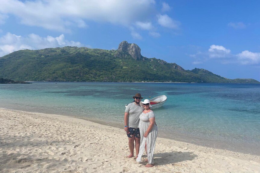 Lachie Dent and Chantelle Bongers standing on a white sand beach in Fiji. 