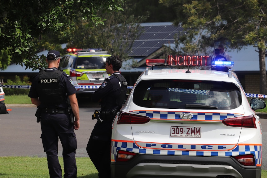 Queensland police officers standing by car with 'Incidient' on top