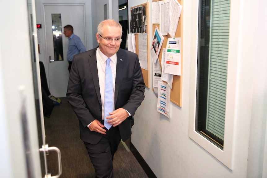 Scott Morrison smiles as he walks corridors of Parliament House