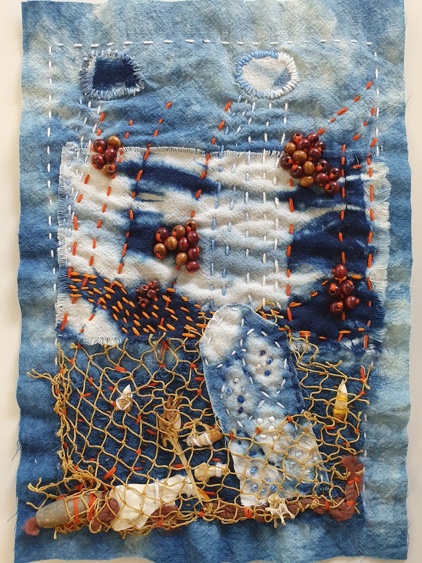 An image of a slow stitched piece with netting and beads for a community quilt.
