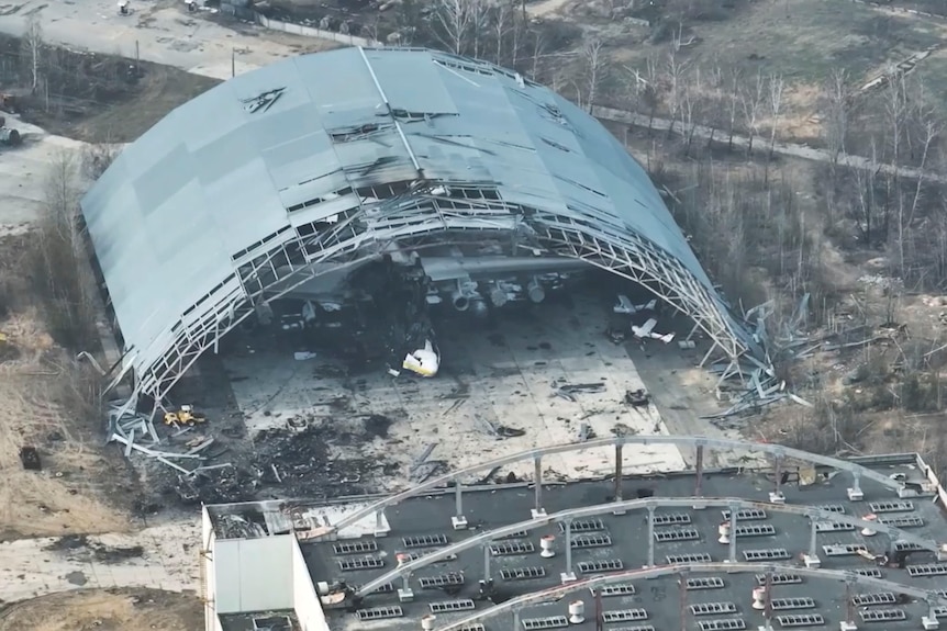 A damaged airplane hanger surrounded by rubble