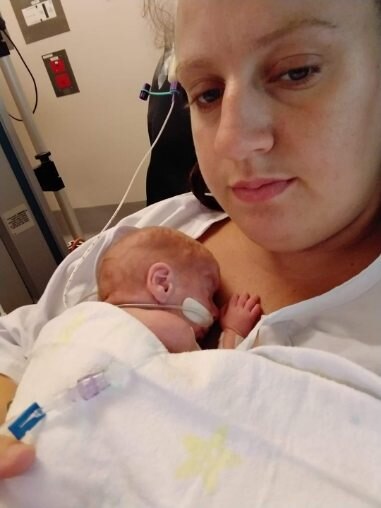 A mother holds her baby on her chest in hospital.