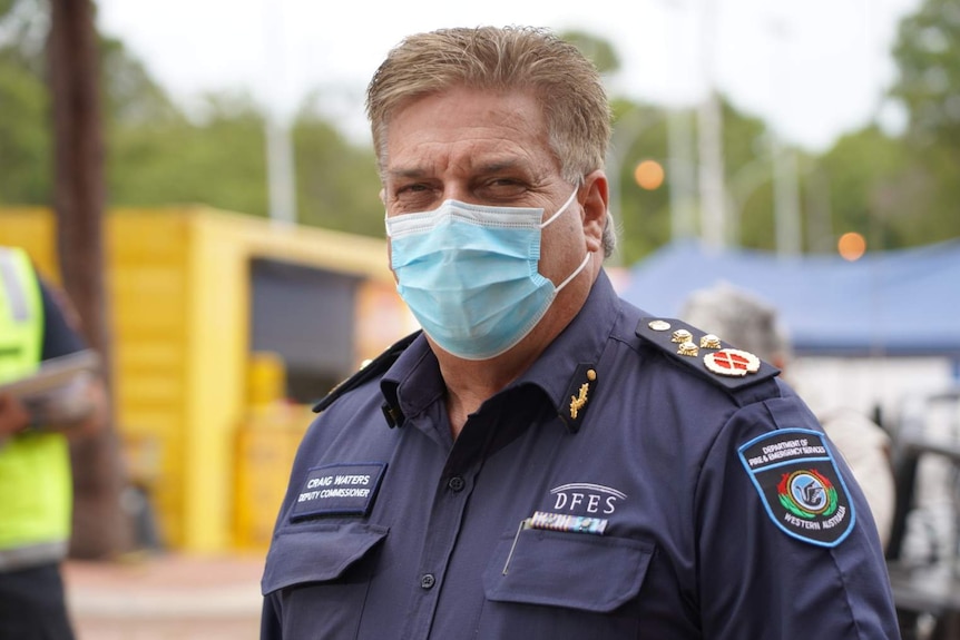 A fire commissioner wearing a mask looks at the camera