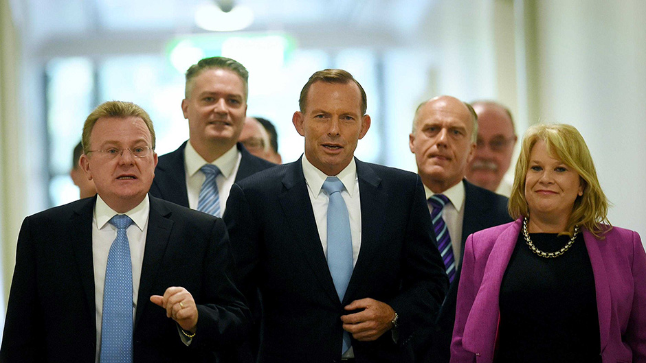Tony Abbott and fellow MPs leave the Liberal party room meeting, where Mr Abbott won a leadership spill vote 61-39.