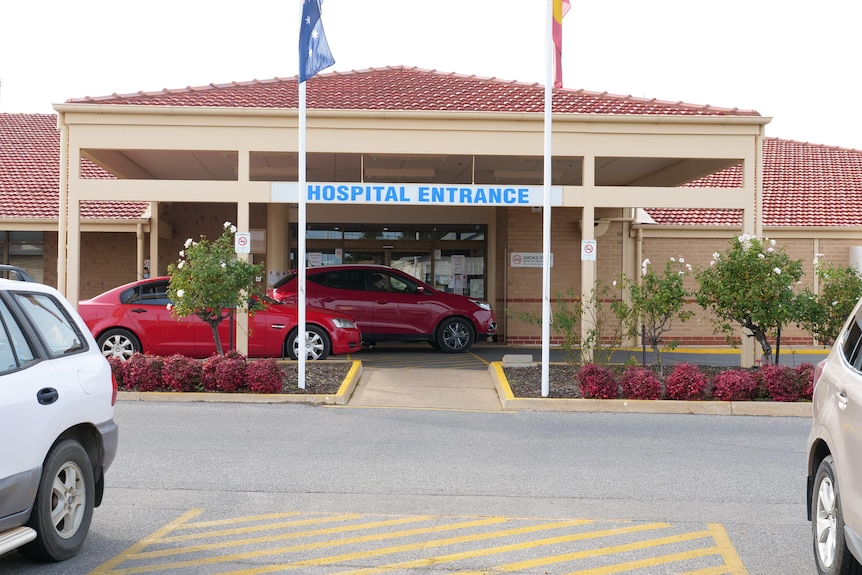 An entrance to a hospital with a driveway and a sign reading 'Hospital Entrance'