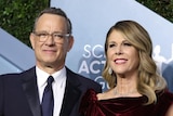 Tom Hanks, left, looks slightly to the right with a frown on his face next to wife Rita Wilson, right, who smiles.
